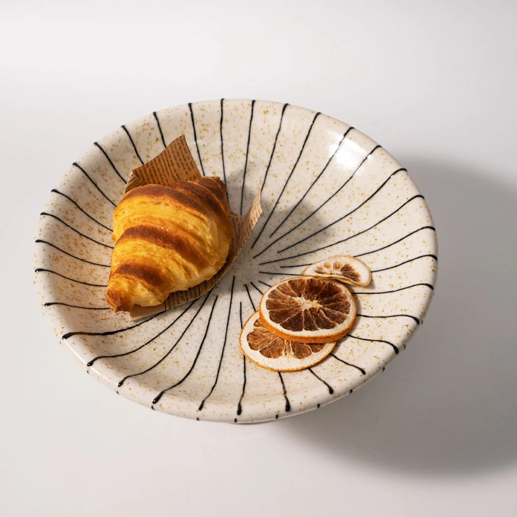 Black and white striped synthetic resin dessert plate on a table.