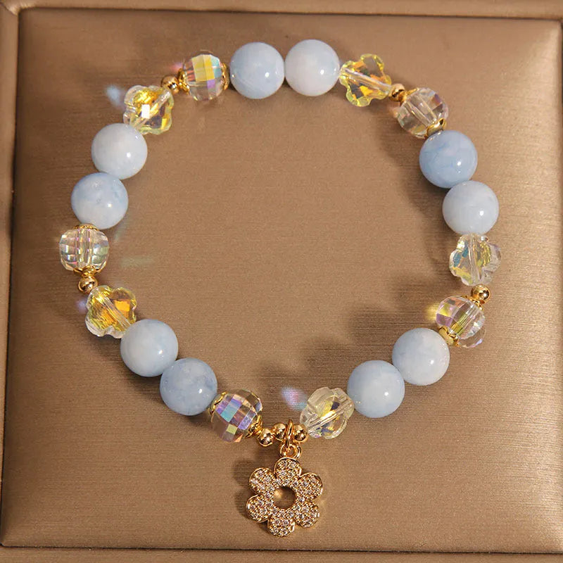 Aquamarine crystal bracelet with a four-leaf clover charm and a pearl decorative element on a wrist.