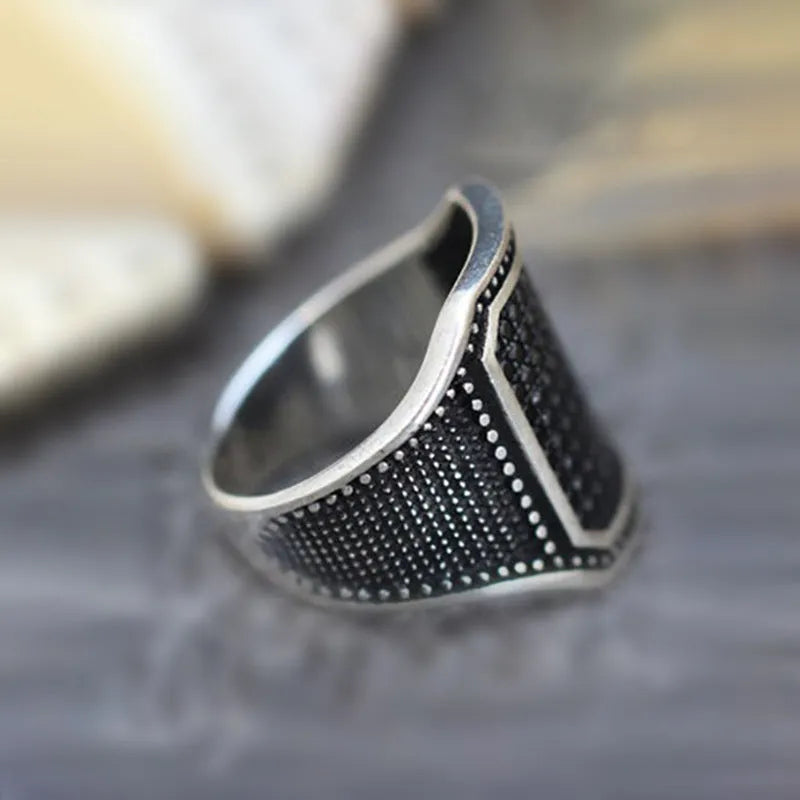 Close-up of a black alloy ring with a zircon stone and copper-coloured inlay detailing on the band.
