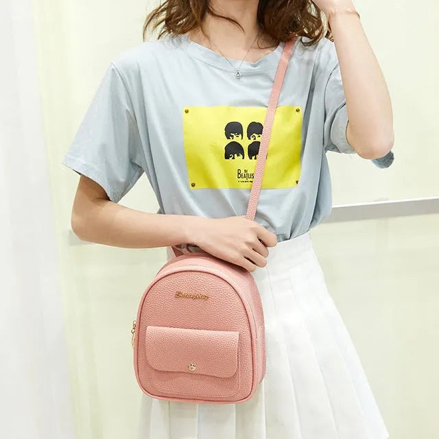 Small black PU leather women's shoulder backpack worn as a backpack, showing zipper closure and compact size.