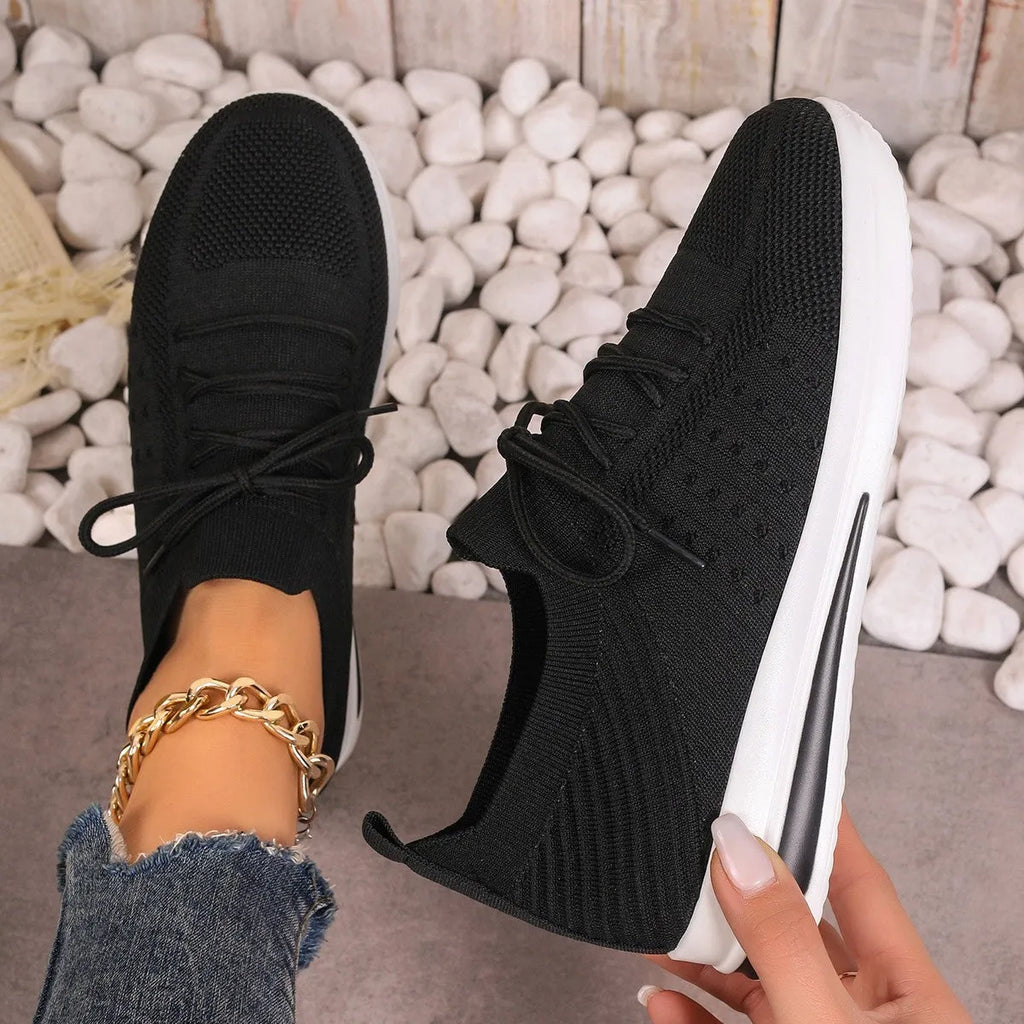 Women's low-top fly-knit style sneakers in black, blue, and red colours with round toe and lace-up front.