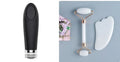 White jade facial roller and gua sha scraper board set on a plain surface.