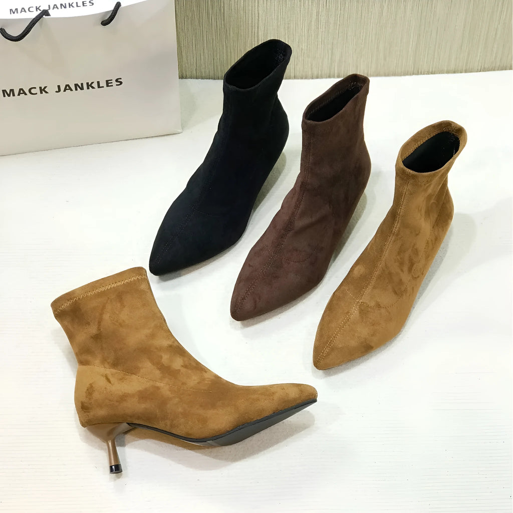 Black pointed toe women's ankle boots with a stiletto heel on a plain background