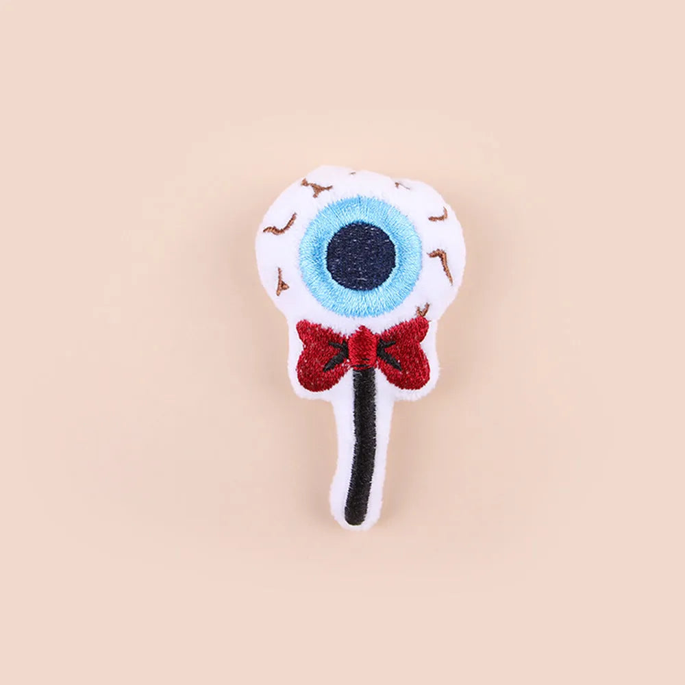 Small plush cat teaser toy in candy, eyes, and skull designs on a blue background.
