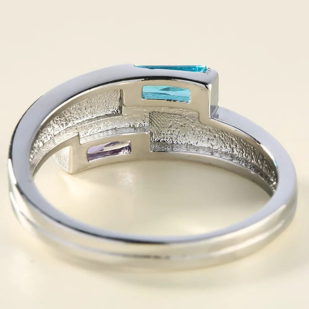 Silver coloured electroplated copper ring with a central inlaid zircon stone on a plain background.