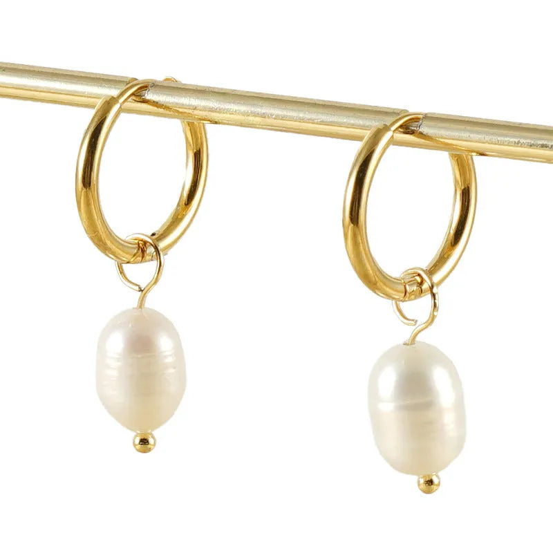 A pair of geometric drop earrings with a gold metal frame and a central freshwater pearl.