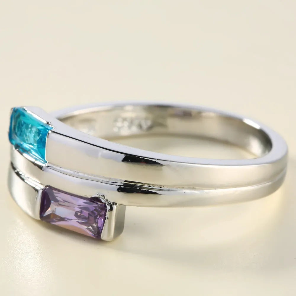 Silver coloured electroplated copper ring with a central inlaid zircon stone on a plain background.