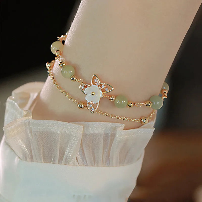 Yellow gold electroplated copper bracelet with shell flower butterfly charm containing Hetian jade elements