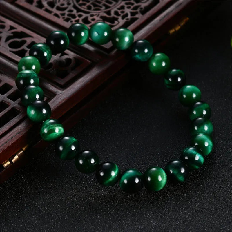 Green tiger eye gemstone bracelet with geometrically polished beads on a white background.