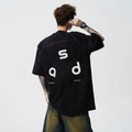 Loose-fitting black cotton T-shirt with a letter print on the chest, showing short sleeves and a round neck.