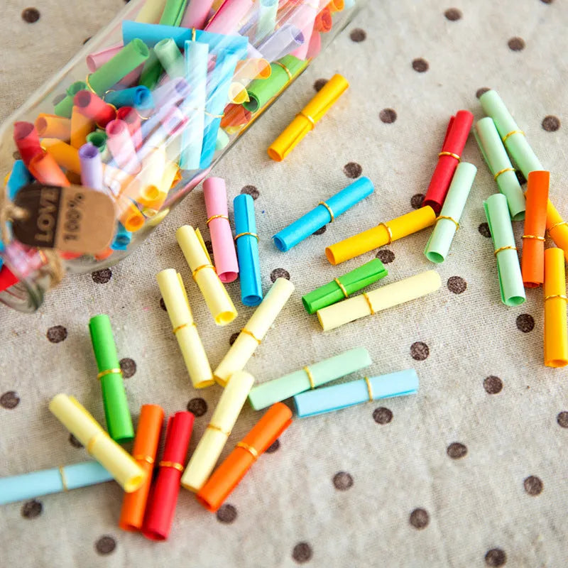 Colourful drift bottle message paper scrolls in various sizes with metal eyelets for hanging.