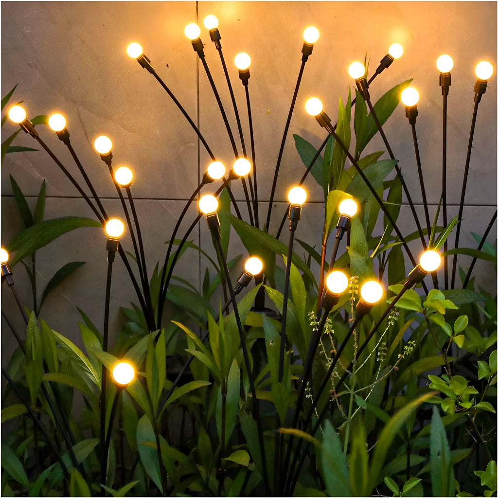 Solar-powered LED firefly ground spike light with multiple heads inserted along a garden path.