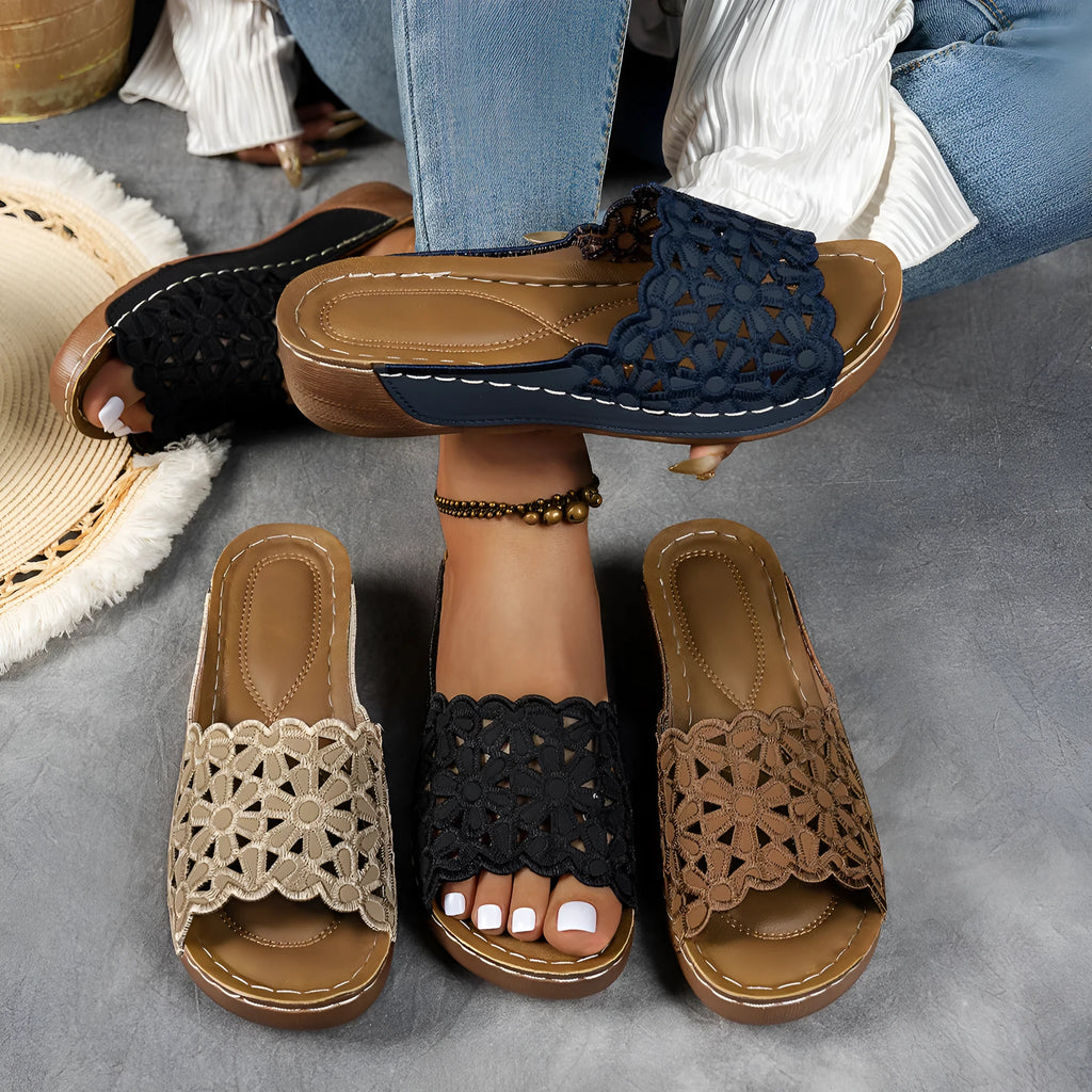 Women's wedge beach slippers with flower cutout design in black colour showing fish mouth toe shape