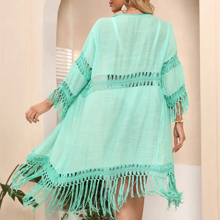 Yellow hand-crocheted acrylic cardigan with tassels, laid flat as a beach cover-up.