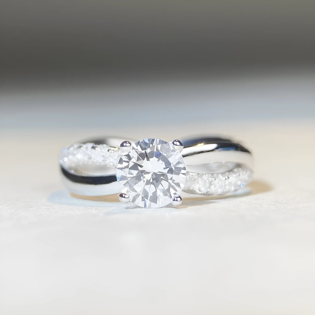 Geometric cross design moissanite ring with twisted sterling silver band and four-claw setting.