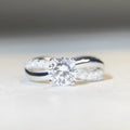 Geometric cross design moissanite ring with twisted sterling silver band and four-claw setting.