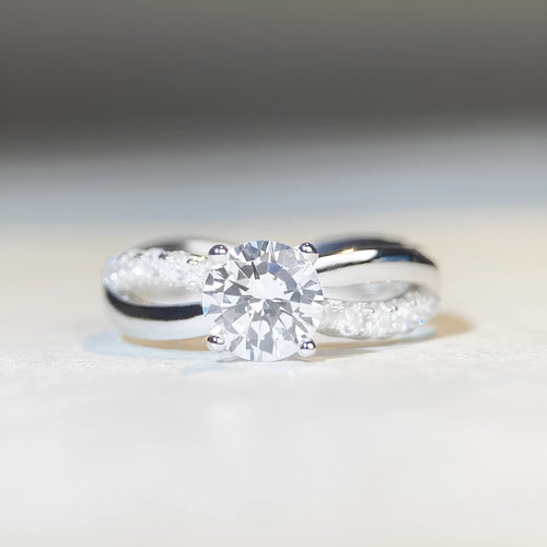 Geometric cross design moissanite ring with twisted sterling silver band and four-claw setting.