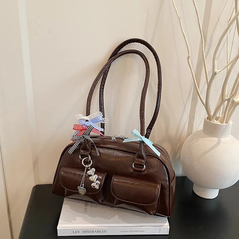 Women's black PU leather retro pillow handbag with double shoulder straps shown carried underarm