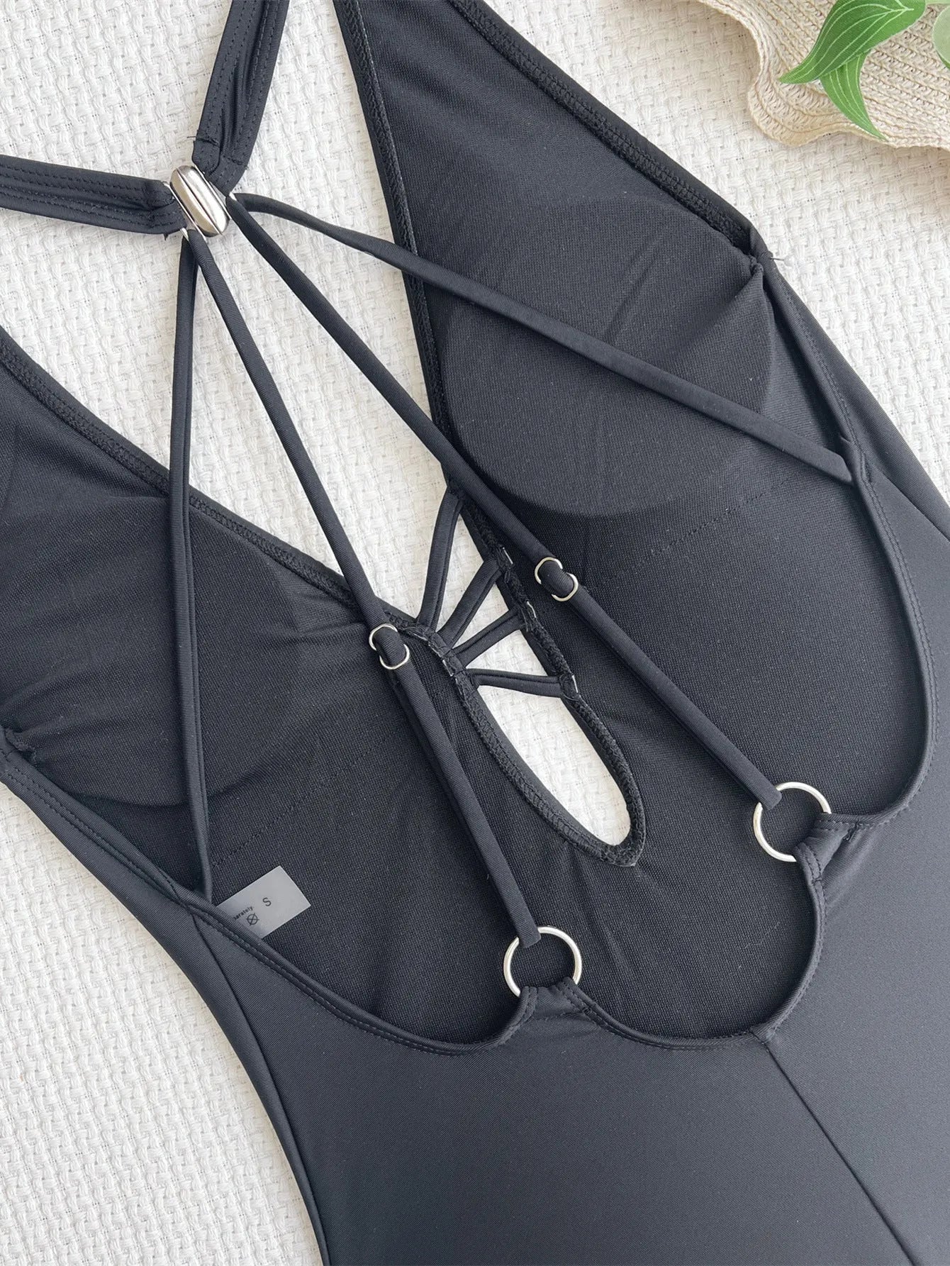 Black solid colour one-piece ladies bikini made from nylon fabric, shown on a size chart.
