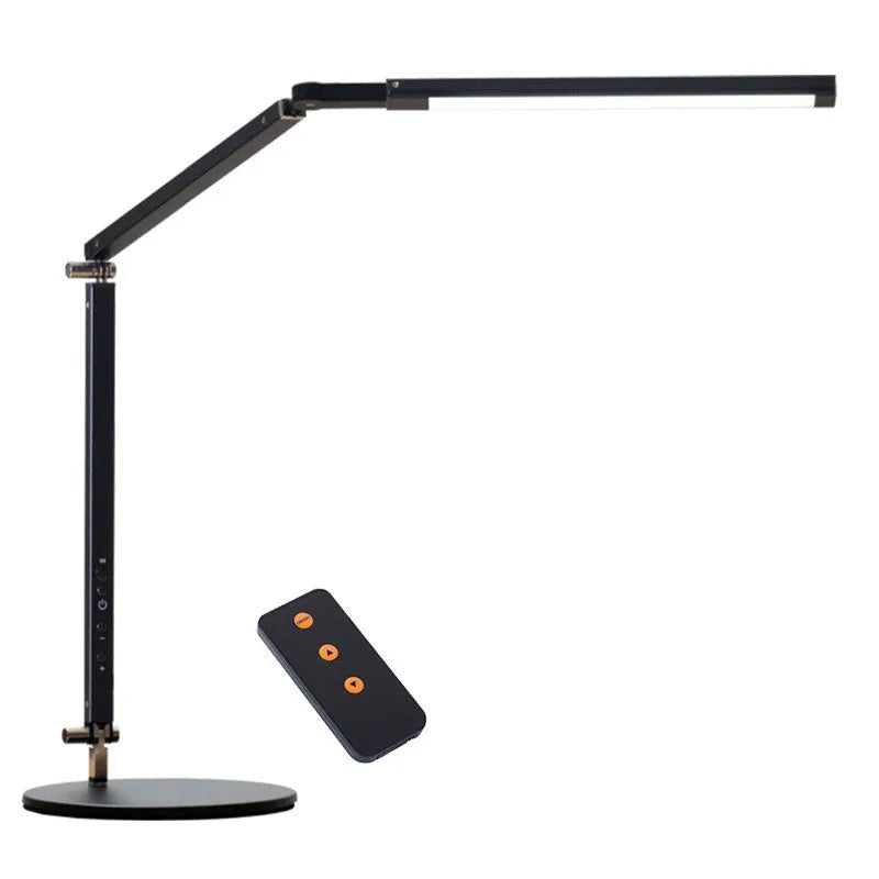 Black folding clip-on LED desk lamp with remote control on a wooden desk.