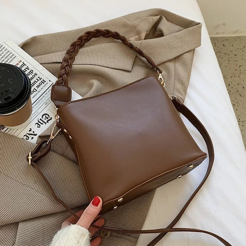 Khaki PU woven one-shoulder crossbody bucket bag with retro design on a mannequin