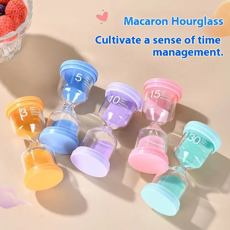 Handmade glass sand timer hourglass in blue, green, pink or purple on a desk.