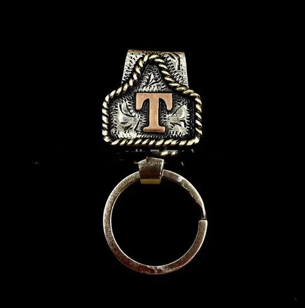 Handmade metal cow tag belt keychain showing the belt loop and one of 26 available alphabet colour options.