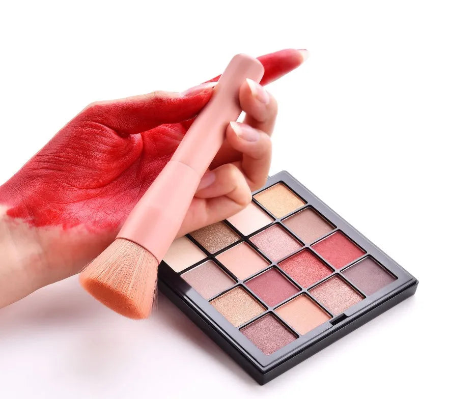 Ten wooden-handle make-up brushes for face and eye application in a pink travel case.