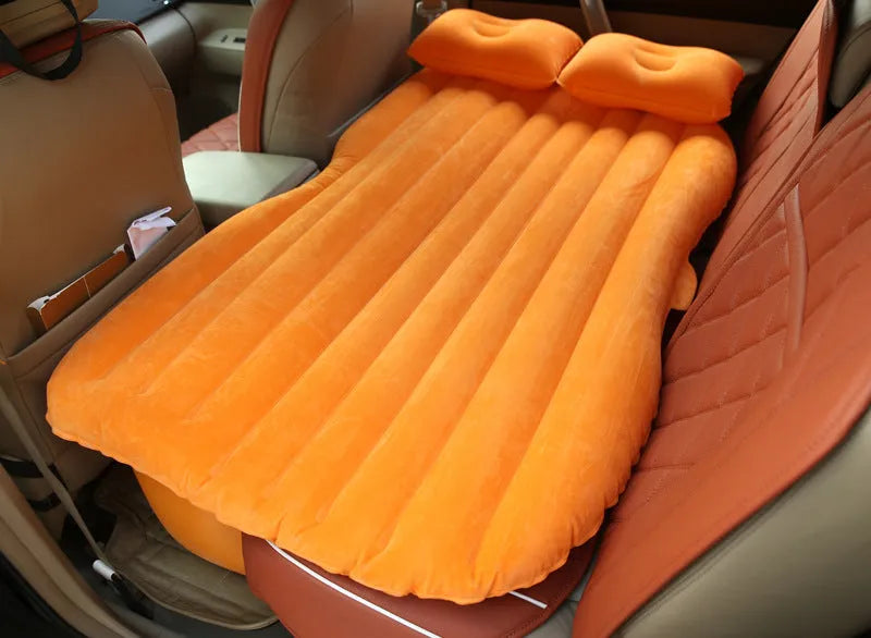 Black inflatable car bed with flocked texture, shown with two pillows inside a car.