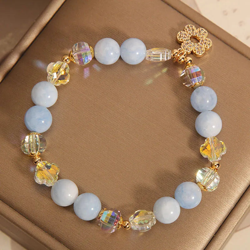 Aquamarine crystal bracelet with a four-leaf clover charm and a pearl decorative element on a wrist.