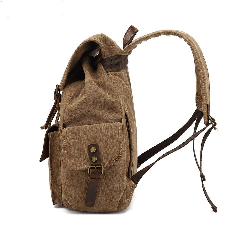 Retro canvas backpack in military green with antique bronze hardware, shown next to a 16-inch laptop.