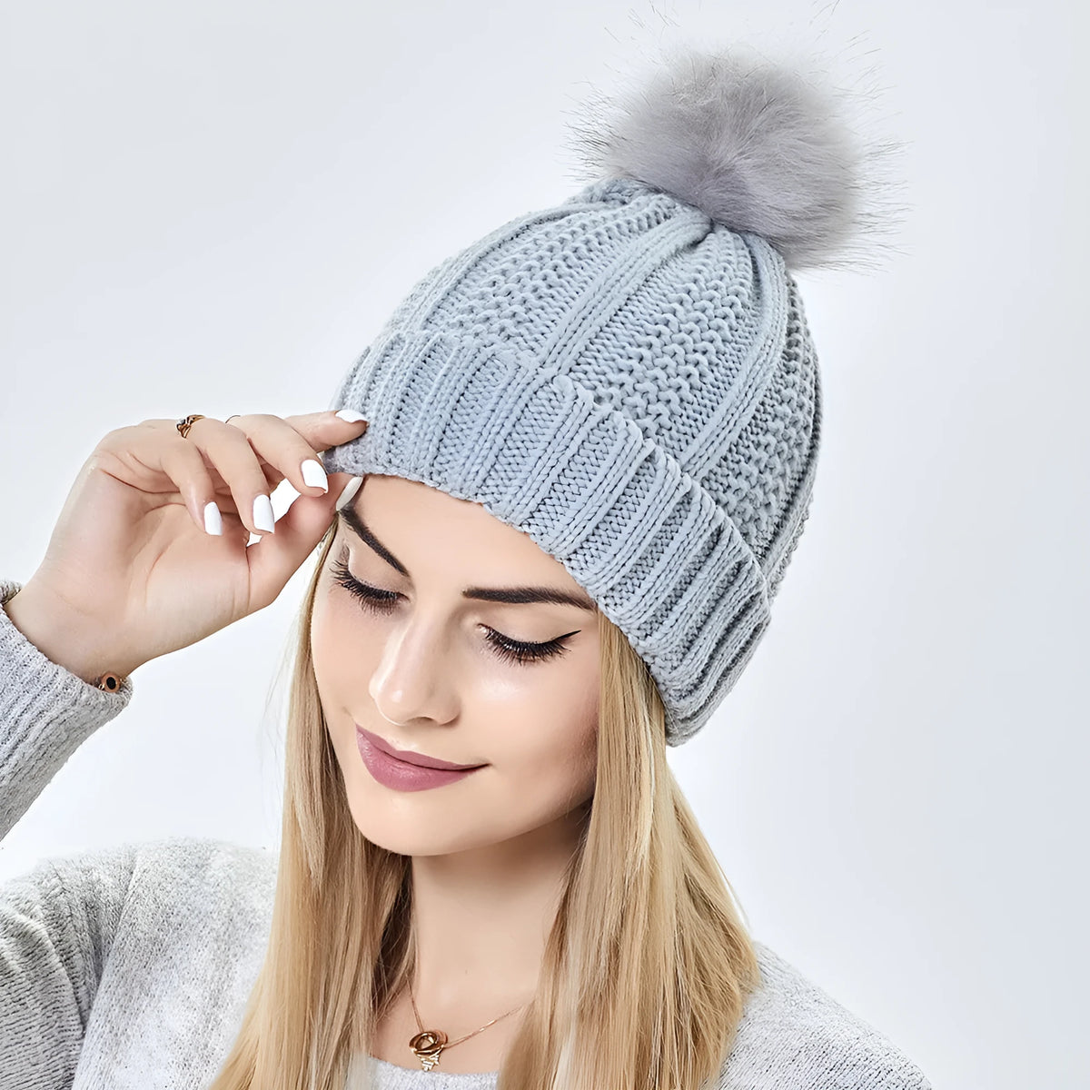 Women's black wool knit beanie with satin lining and a white faux fur pom pom