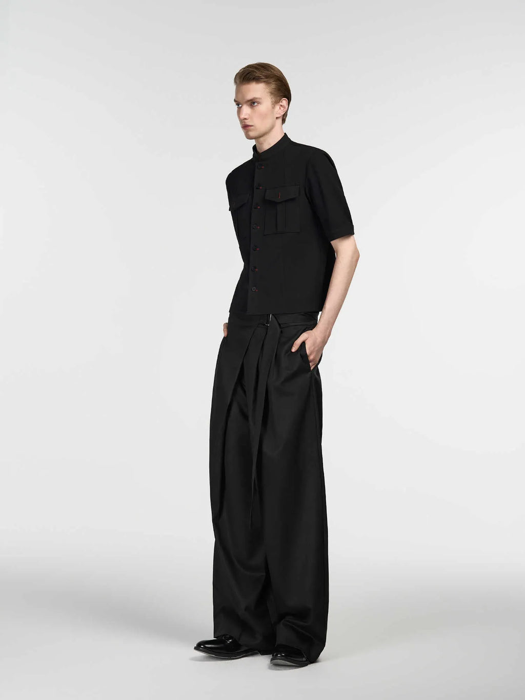 Black straight-leg trousers with a single front pleat and adjustable waistband on a hanger.