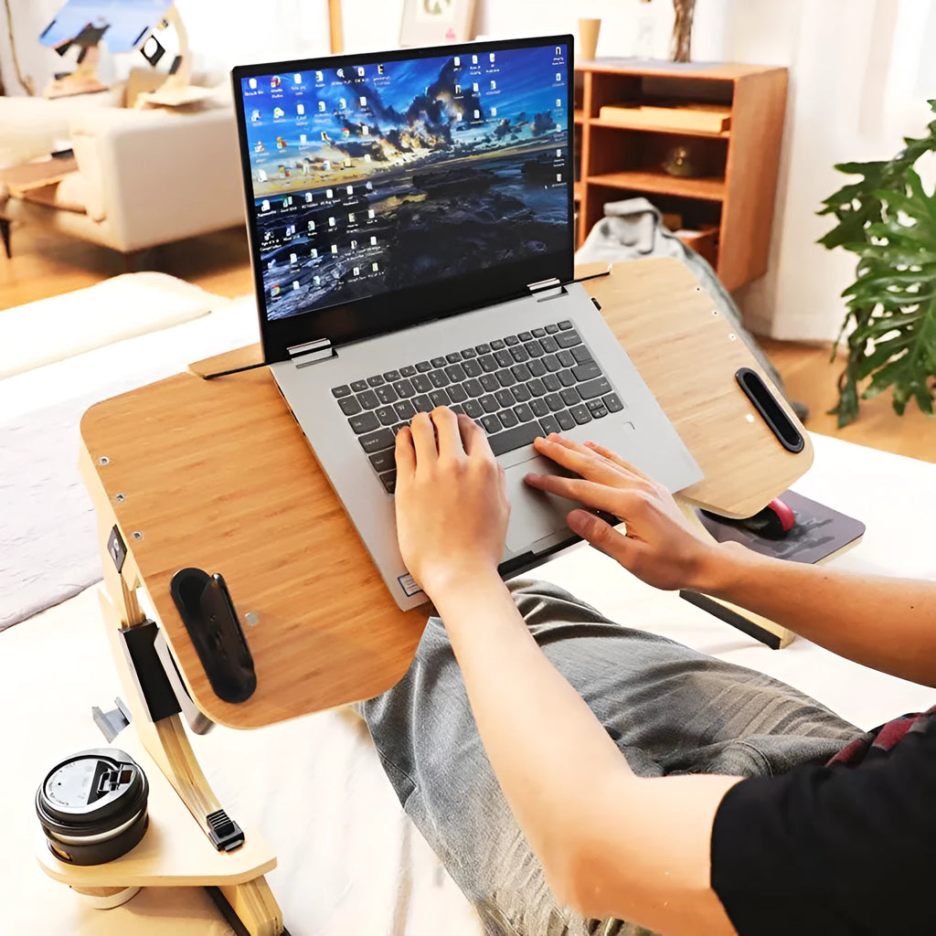 Wooden folding laptop table with adjustable angle on a bed, in black finish.