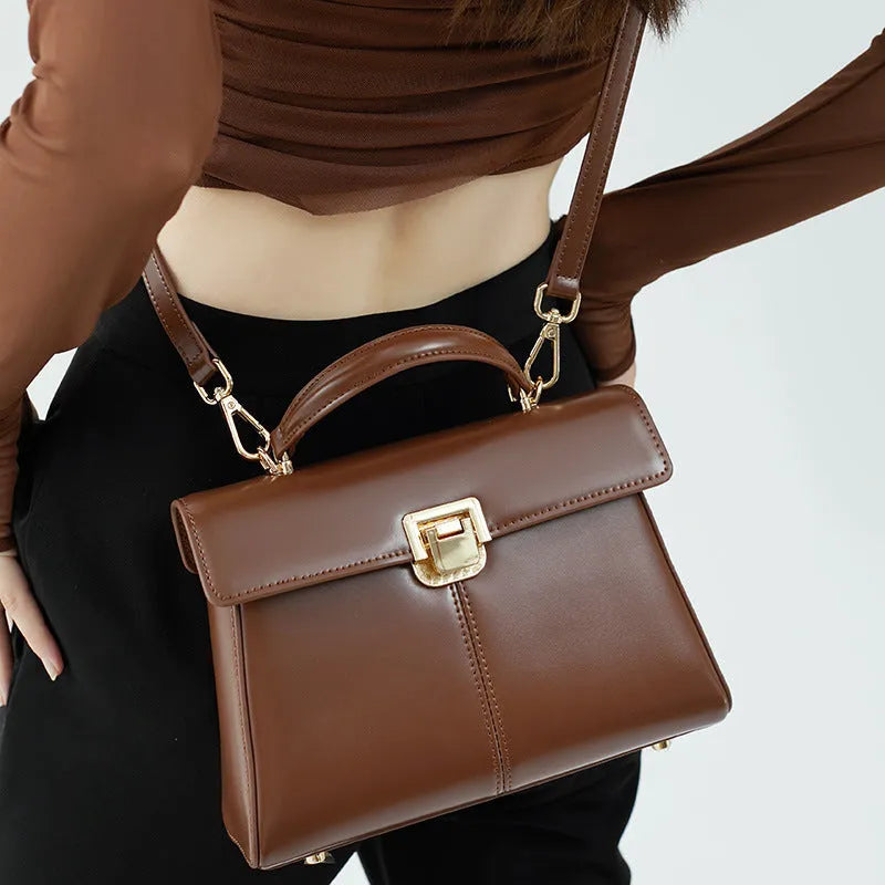 Women's black leather shoulder bag with vachette clasp showing internal zippered pocket