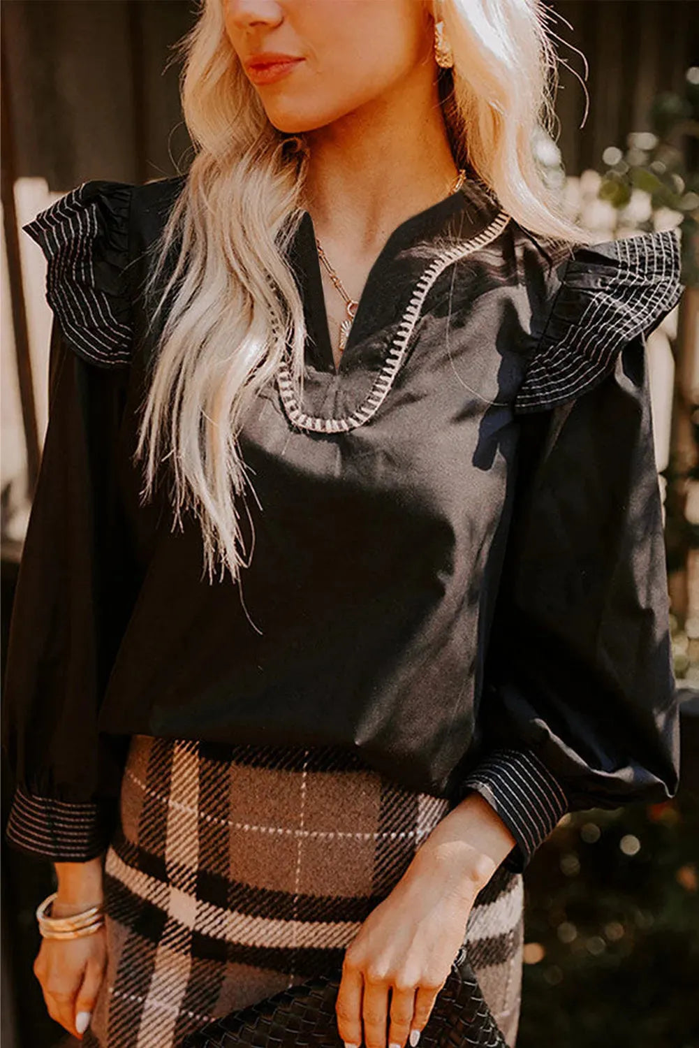 Black long sleeve V-neck blouse for women featuring ruffle details and visible contrast stitching on the seams.