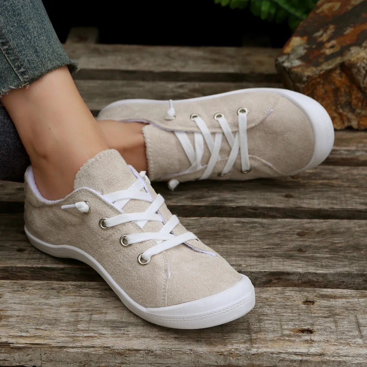 Women's creamy-white low-top fabric sneakers with a rubber sole on a neutral background.