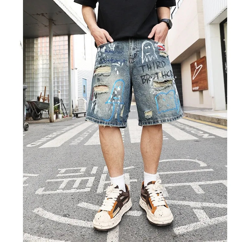 Blue denim shorts for men with ripped knees and graffiti print, featuring a straight leg and a zipper fly