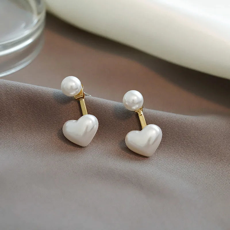 Women's silver-toned heart-shaped stud earrings with central gemstone inlay on a white background.