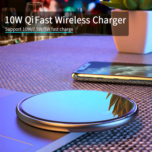 Black Qi fast wireless charging pad on a desk next to a smartphone, showing a blue LED charging indicator light.