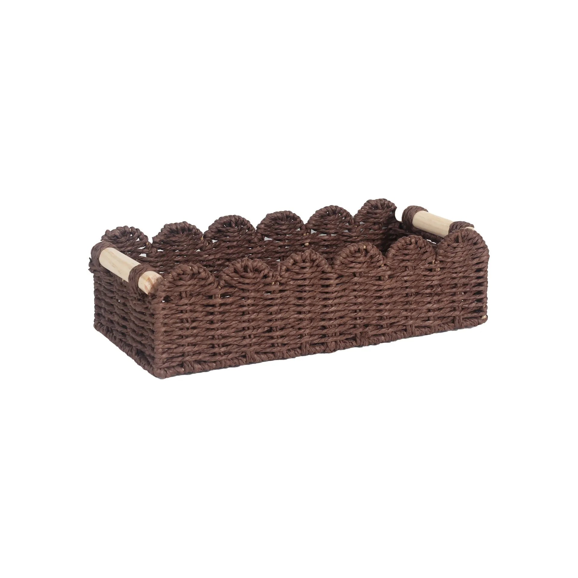 Woven paper storage basket in khaki colour on a wooden desk holding remote controls and pens.