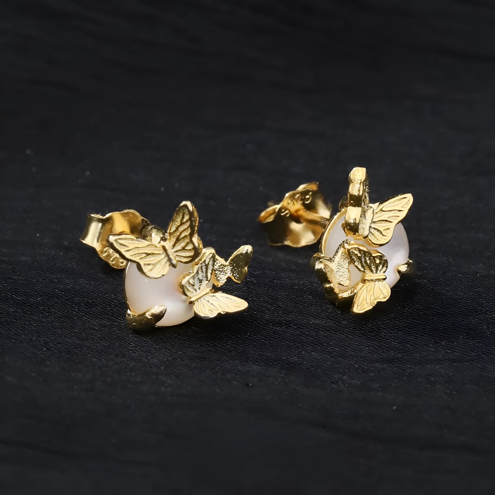 Close-up of 925 silver butterfly stud earrings with animal detail in gold tone finish.