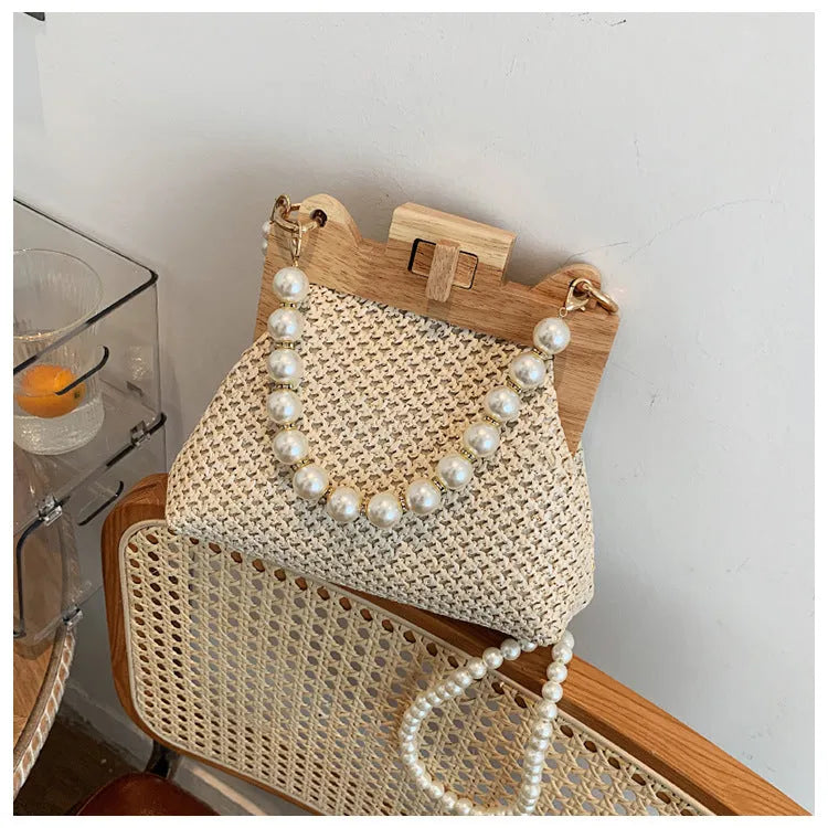 Women's woven straw beach bag with pearl chain shoulder strap in horizontal square shape