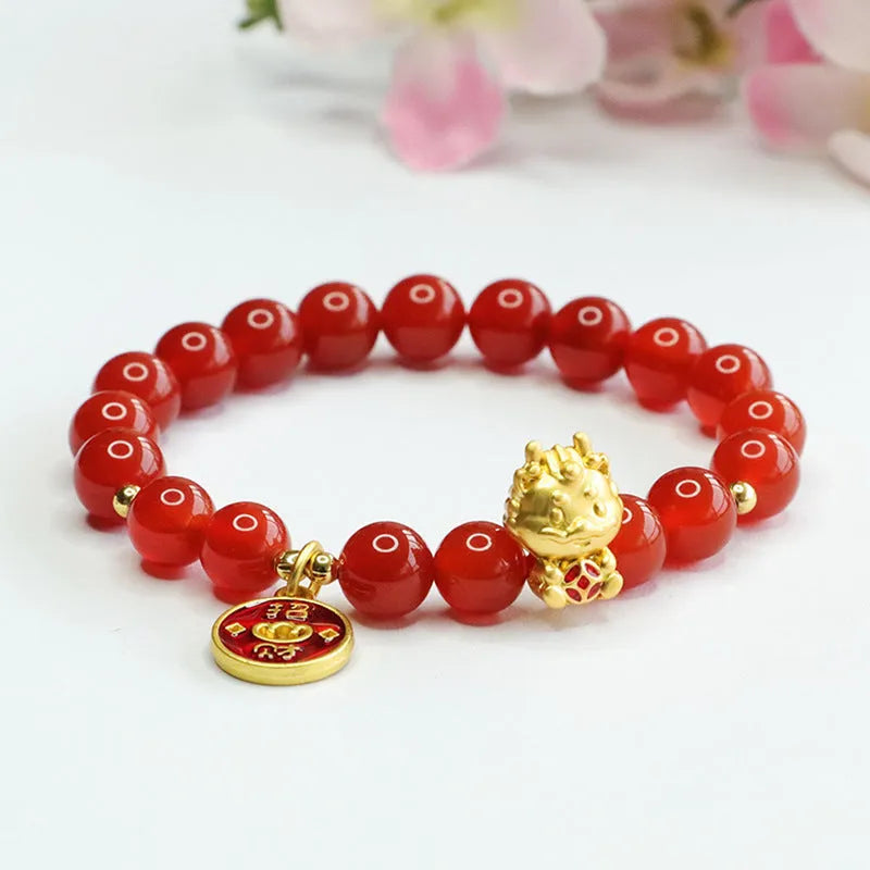Close-up of a red agate beaded bracelet with a dragon zodiac charm on a wrist.