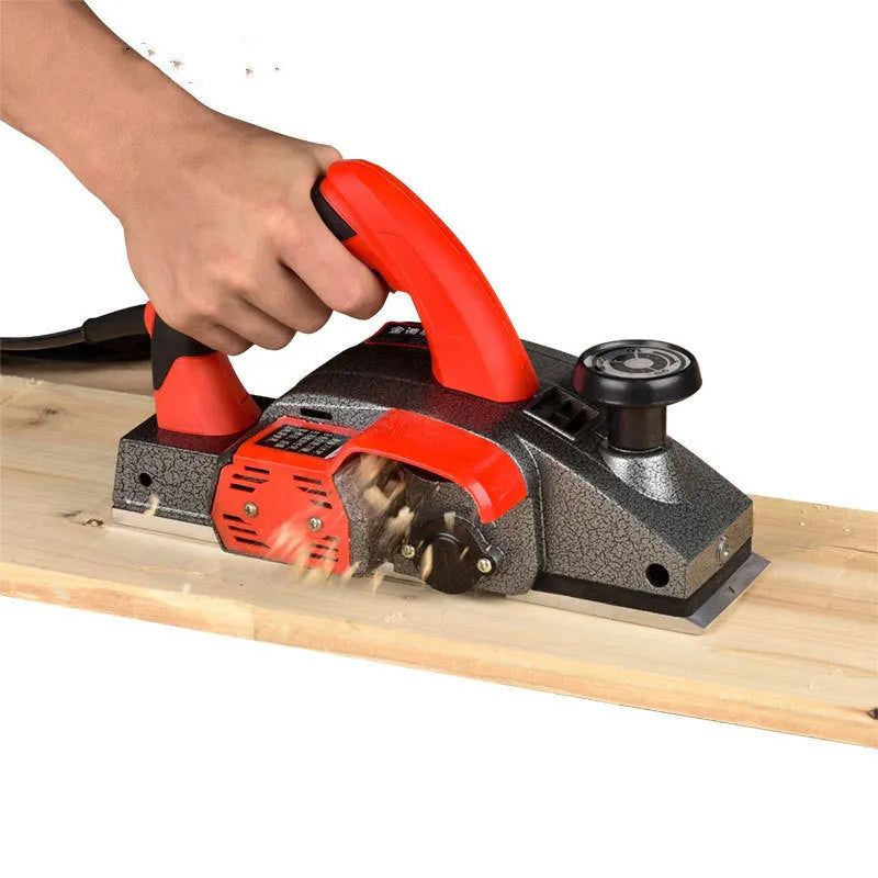 Red aluminium electric wood planer tool with 82mm cutting width on workbench