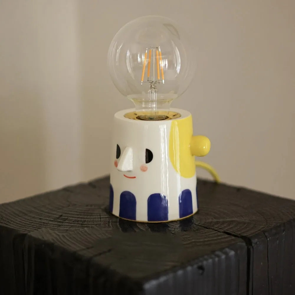 Handmade ceramic ball headlight bedside lamp on a table.