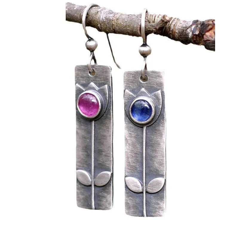 Antique finish red sapphire earrings with elliptical gemstones in a geometric design.
