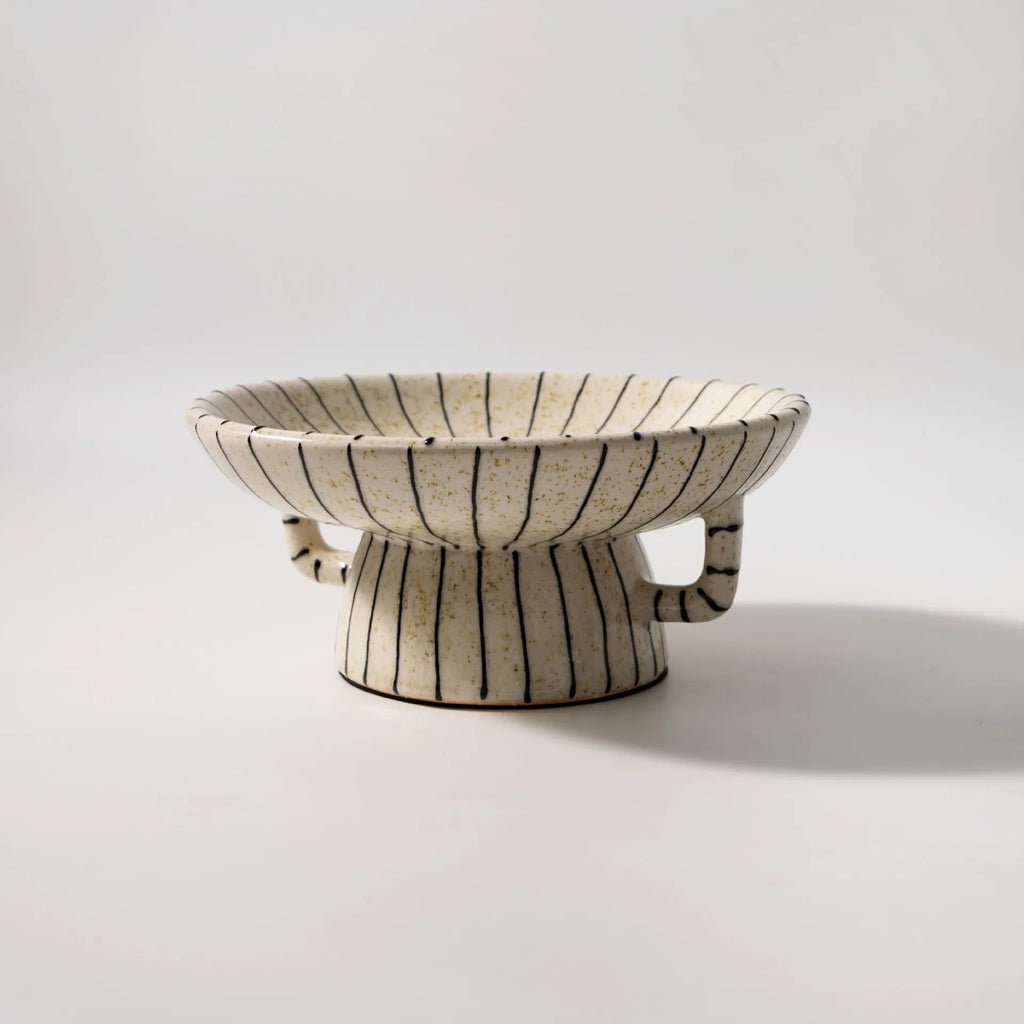 Black and white striped synthetic resin dessert plate on a table.