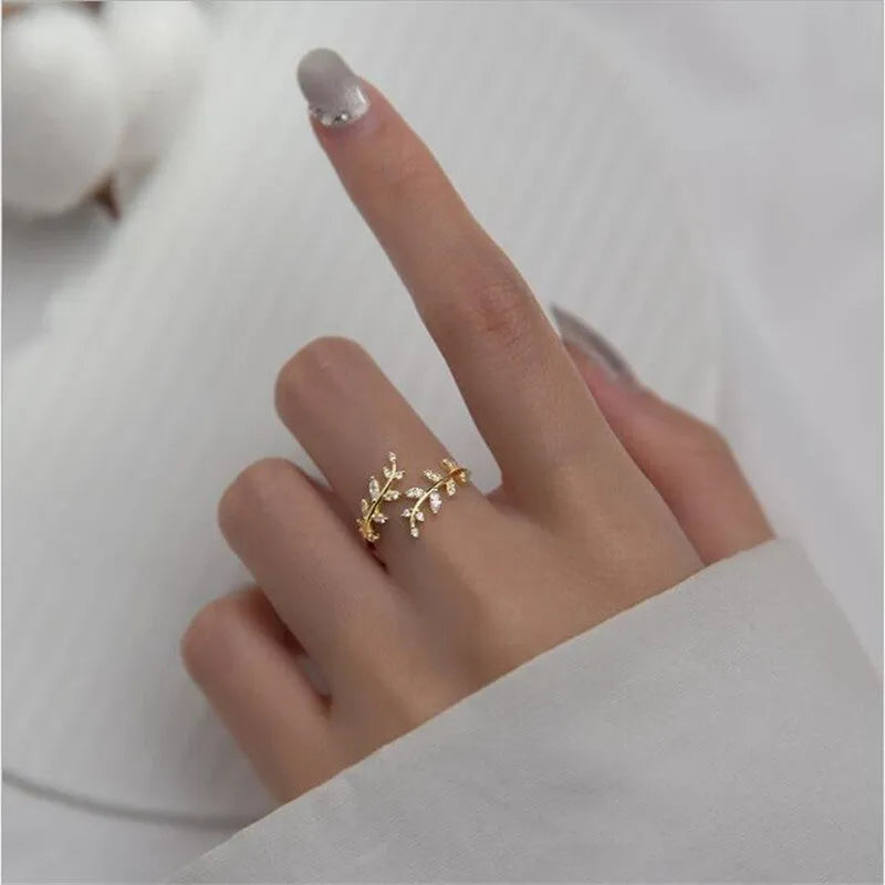 Close-up of a women's leaf-shaped branch fashion ring in a silver or gold electroplated finish on a copper base.