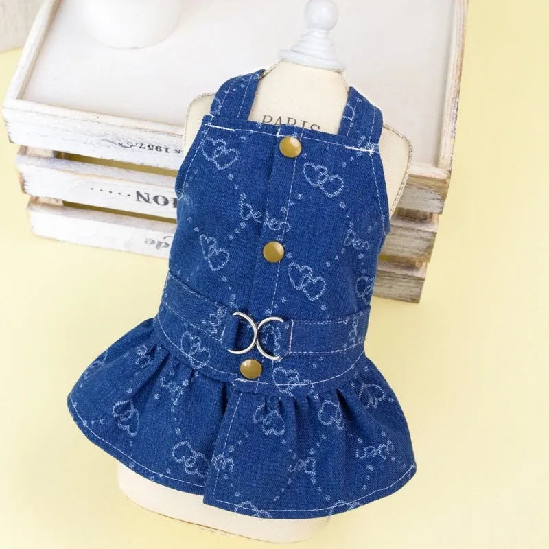 Small white dog wearing a light blue denim bracket-skirt princess dress.